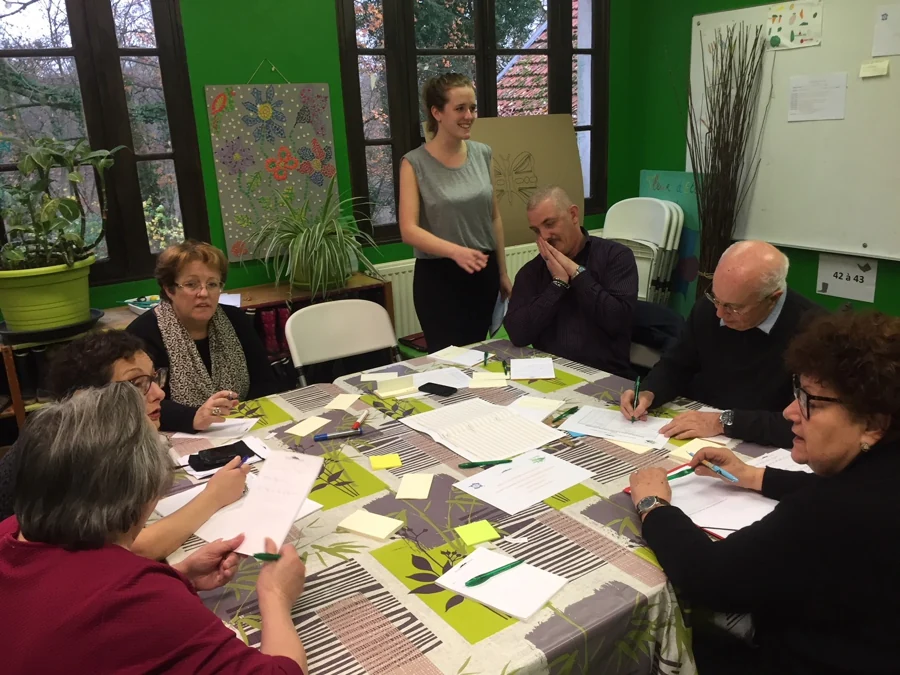 Un groupe échange autour de documents avec une animatrice pendant un atelier citoyen.