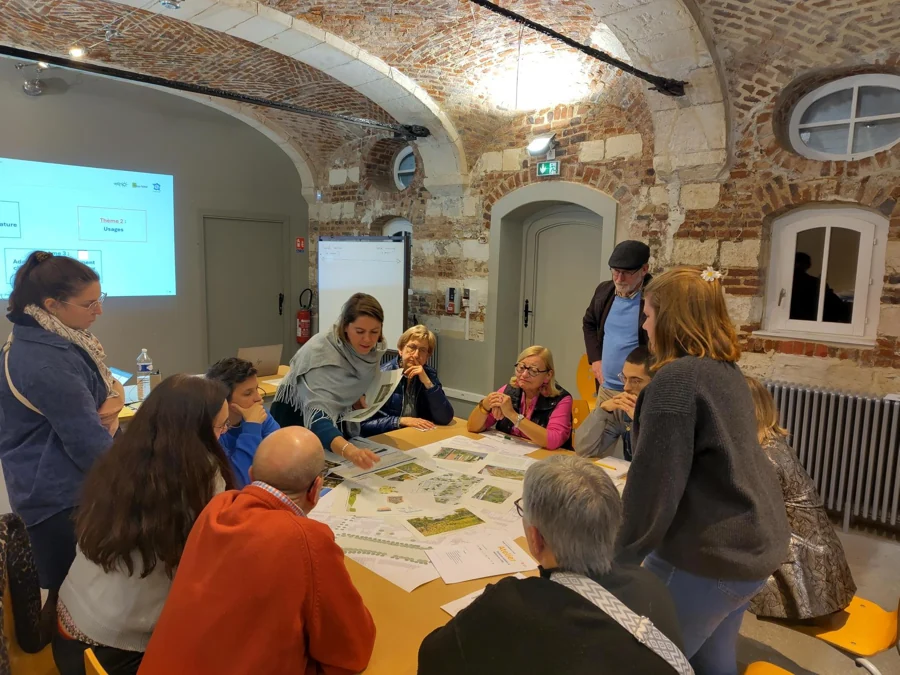 Des participants échangent autour de plans et de propositions pendant un atelier.