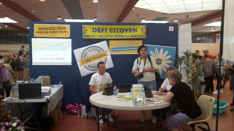 Des participants échangent autour d’un stand Défi citoyen lors d’un forum.